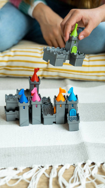 Children playing with a toy castle set on a striped blanket