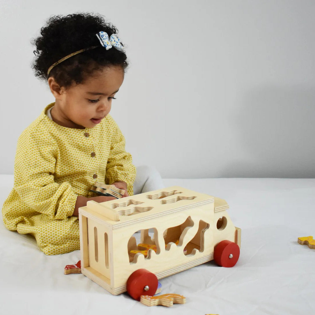 Child playing with a wooden toy on a white surface