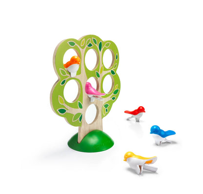 A wooden bird tree toy with a green leafy tree silhouette, circular openings, and small colorful birds in red, blue, yellow, and pink perched inside and around it, shown on a white background.